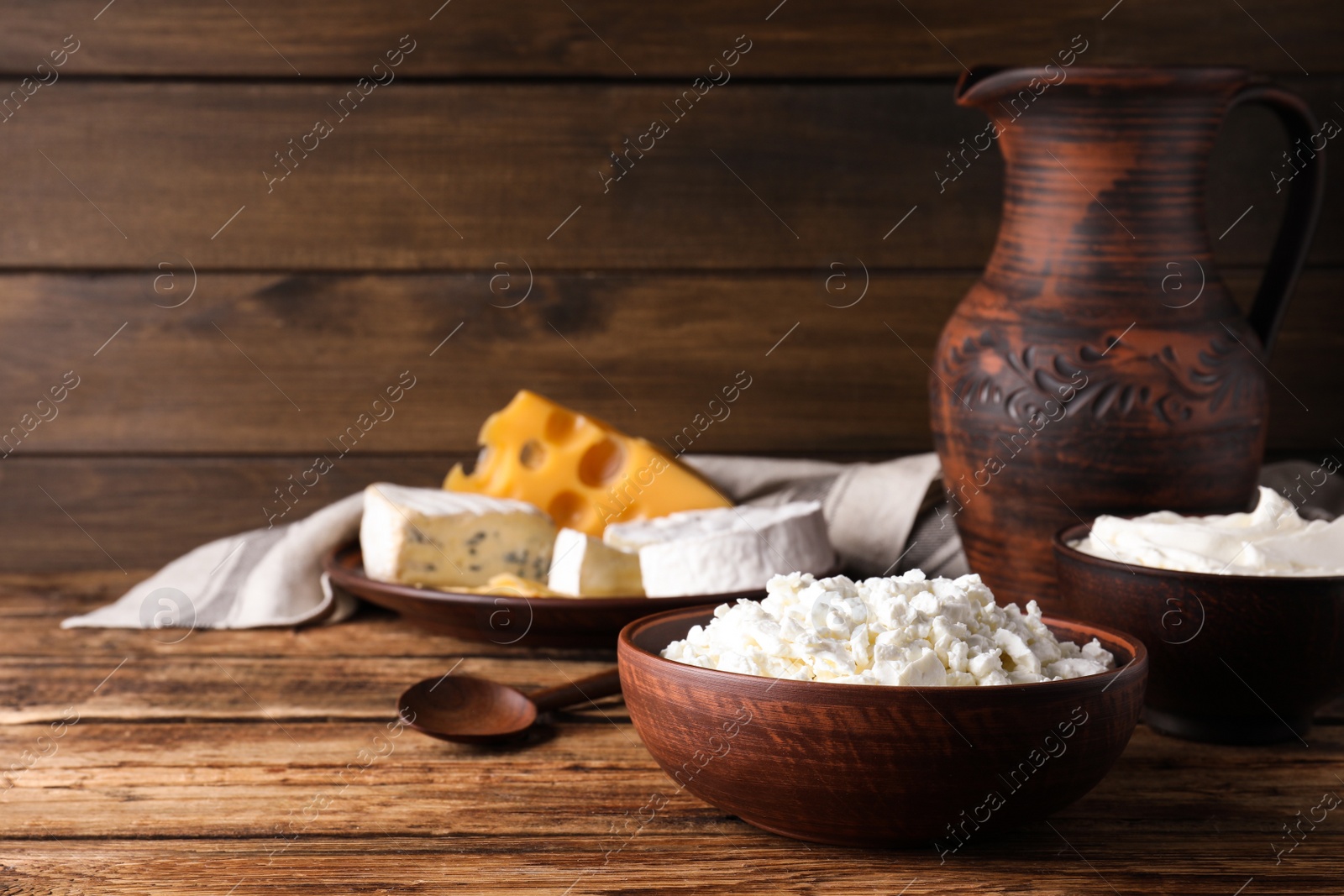 Photo of Clay dishware with dairy products on wooden table. Space for text