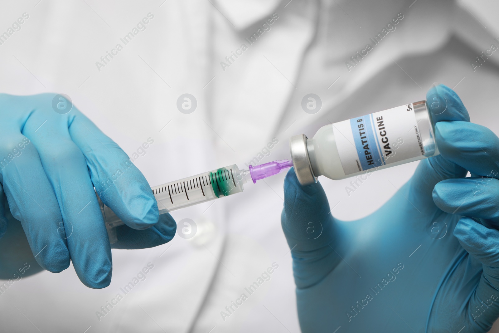 Photo of Doctor filling syringe with hepatitis vaccine from glass vial, closeup