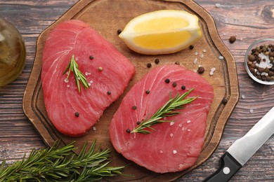 Raw tuna fillets, with rosemary, lemon and peppercorns on wooden table, top view