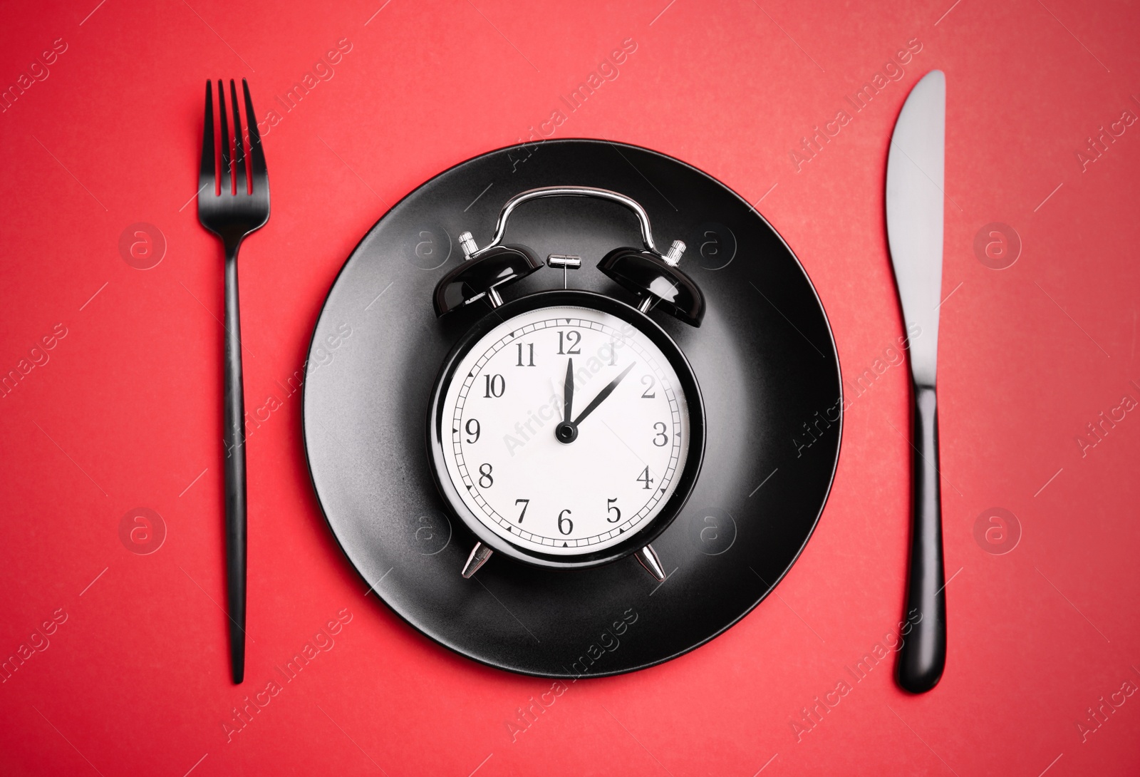 Photo of Alarm clock, plate and cutlery on red background, flat lay. Diet regime