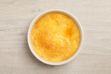 Photo of Delicious creme brulee in ceramic ramekin on white wooden table, top view