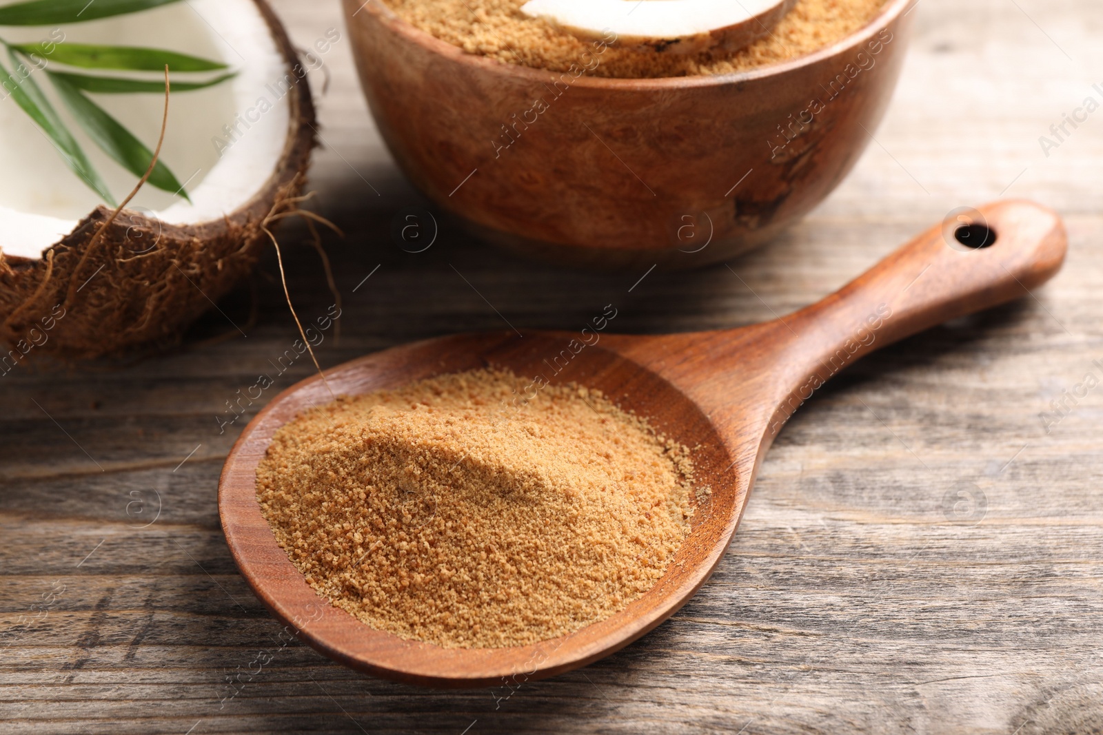 Photo of Spoon with coconut sugar on wooden table, closeup