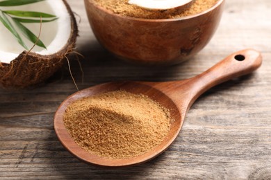 Photo of Spoon with coconut sugar on wooden table, closeup