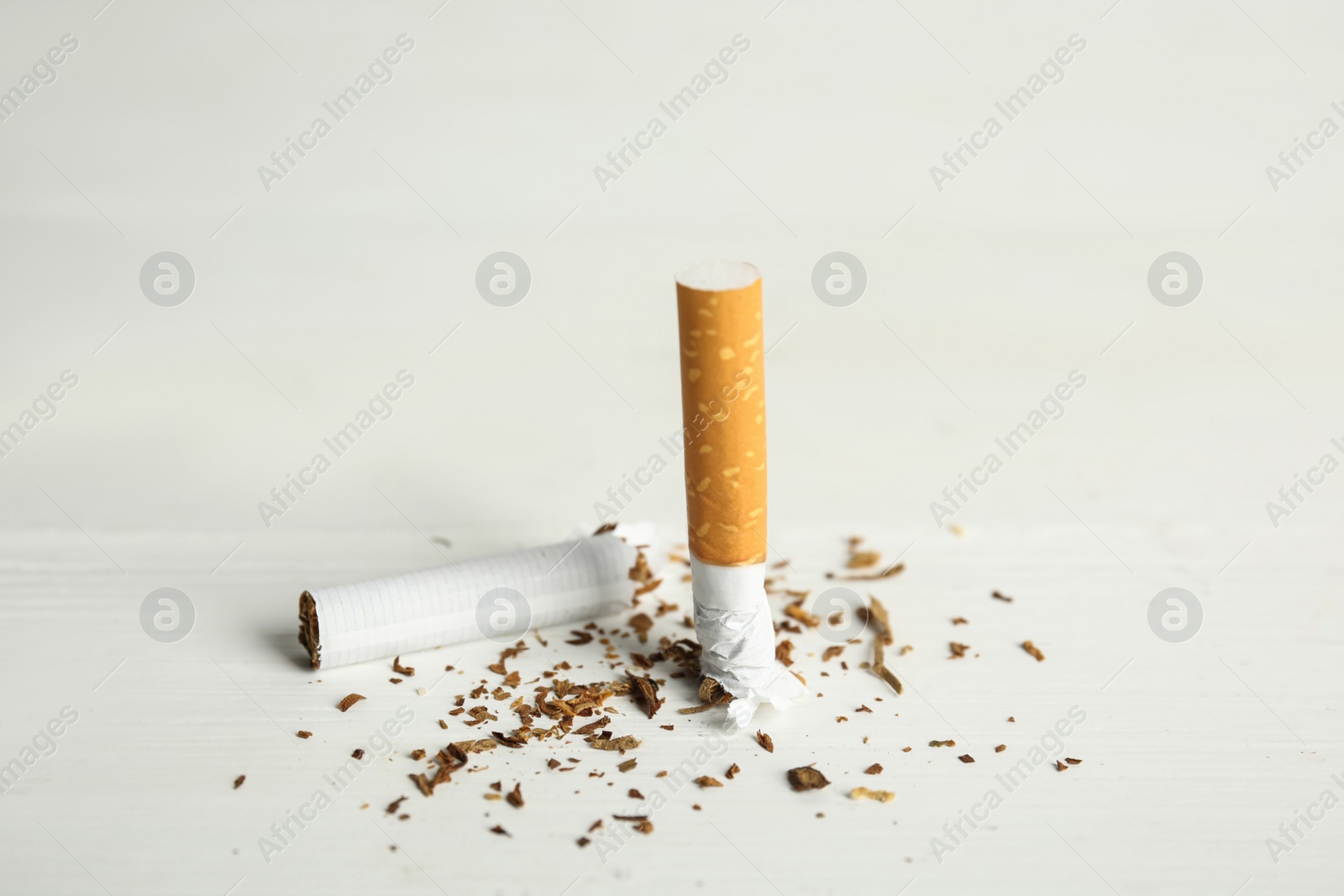 Photo of Broken cigarette on white table. Quitting smoking concept