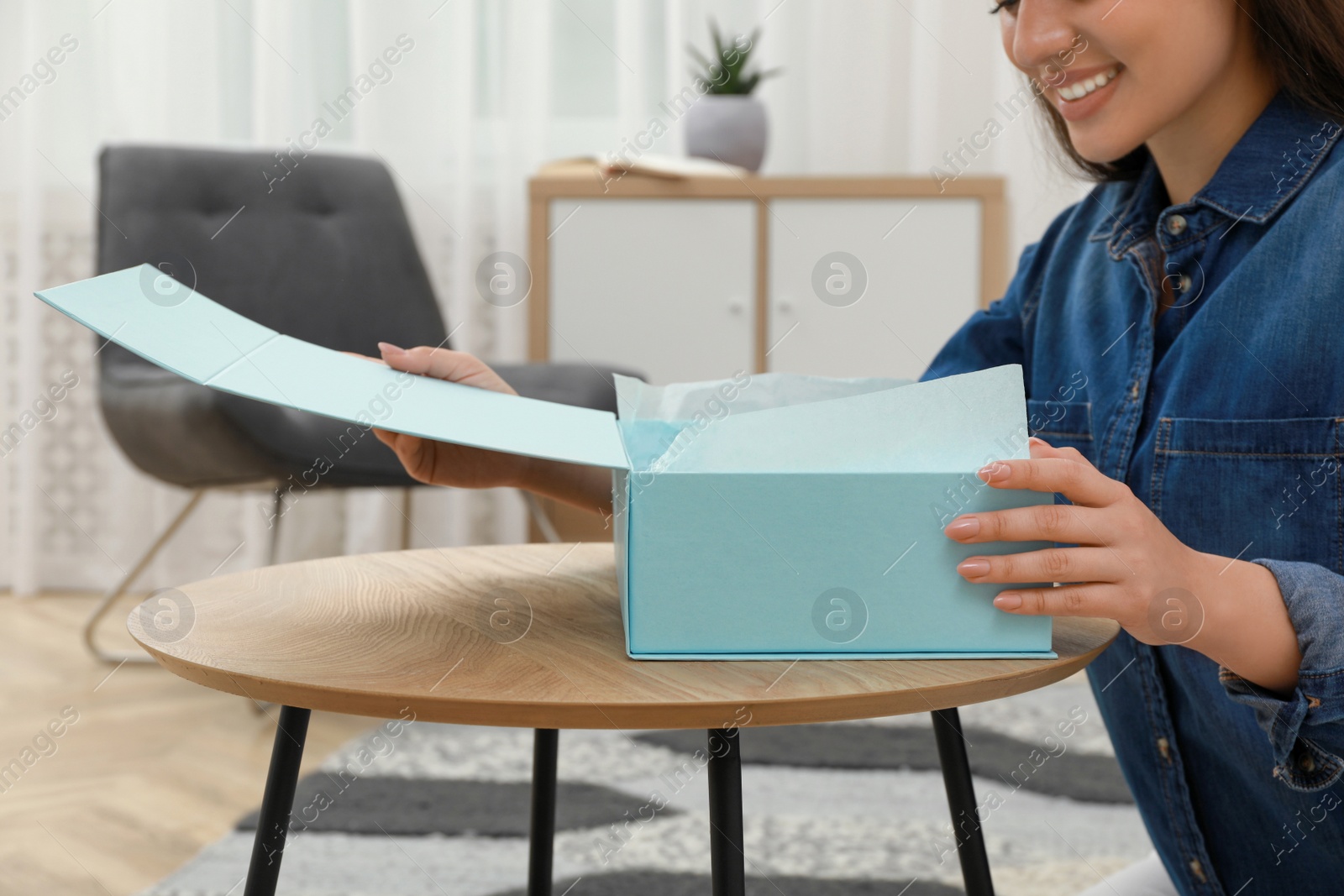 Photo of Happy young woman with parcel at home, closeup. Internet shopping