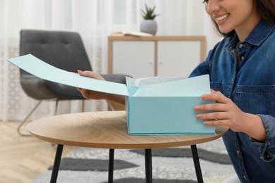 Happy young woman with parcel at home, closeup. Internet shopping