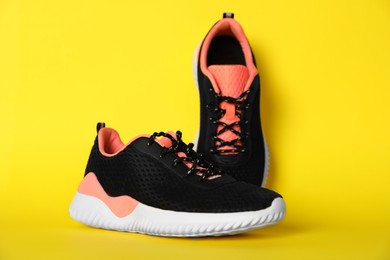 Pair of stylish sport shoes on yellow background