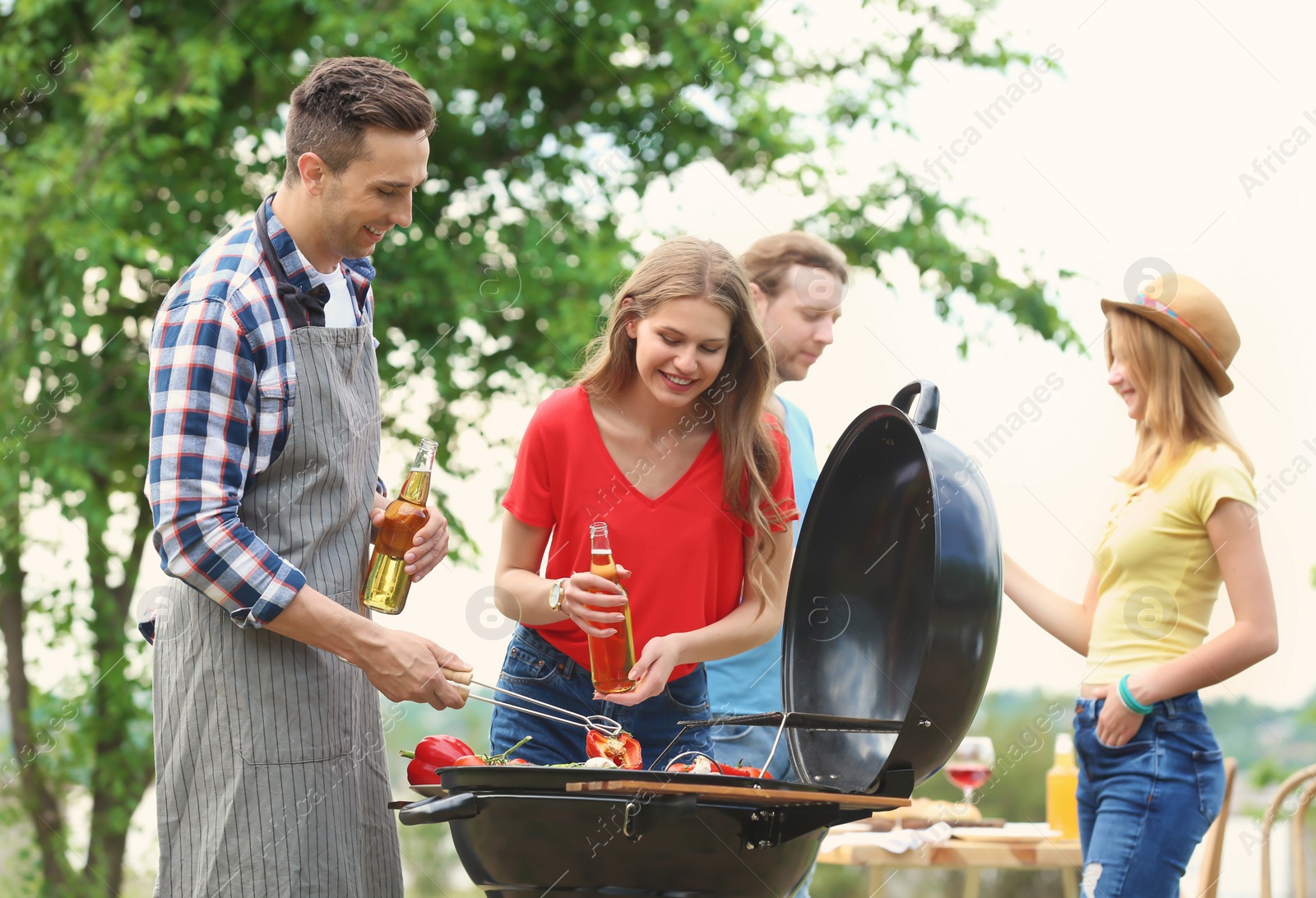 Photo of Young people having barbecue with modern grill outdoors