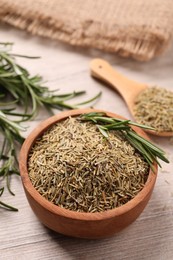 Bowl with dry and fresh rosemary on white wooden table