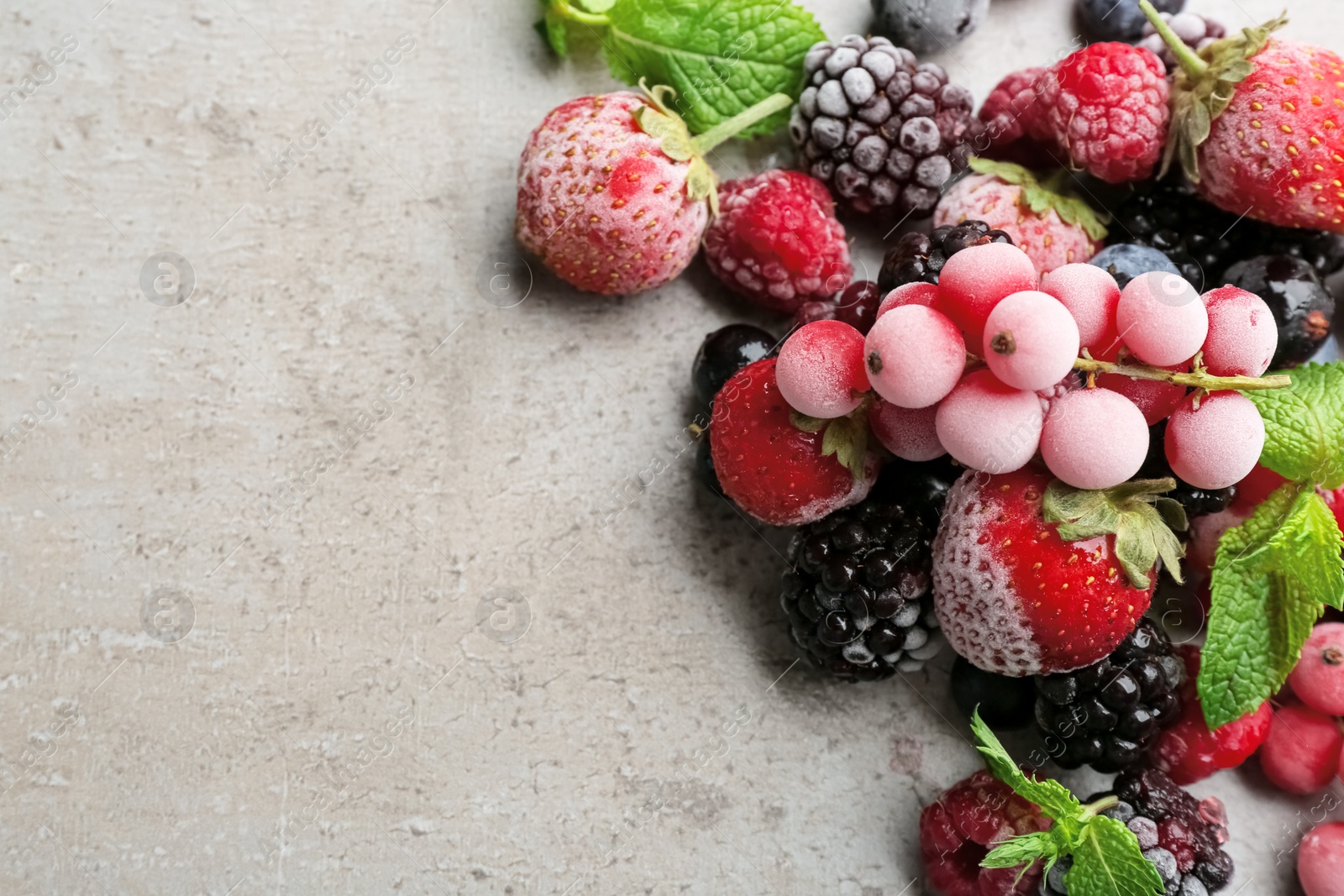 Photo of Mix of different frozen berries on grey table, flat lay. Space for text