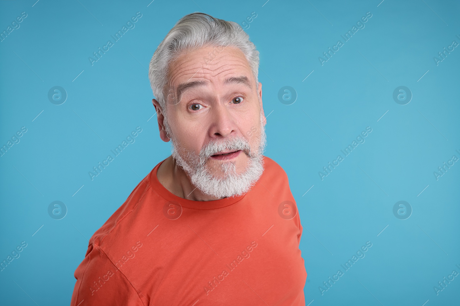 Photo of Portrait of surprised senior man on light blue background