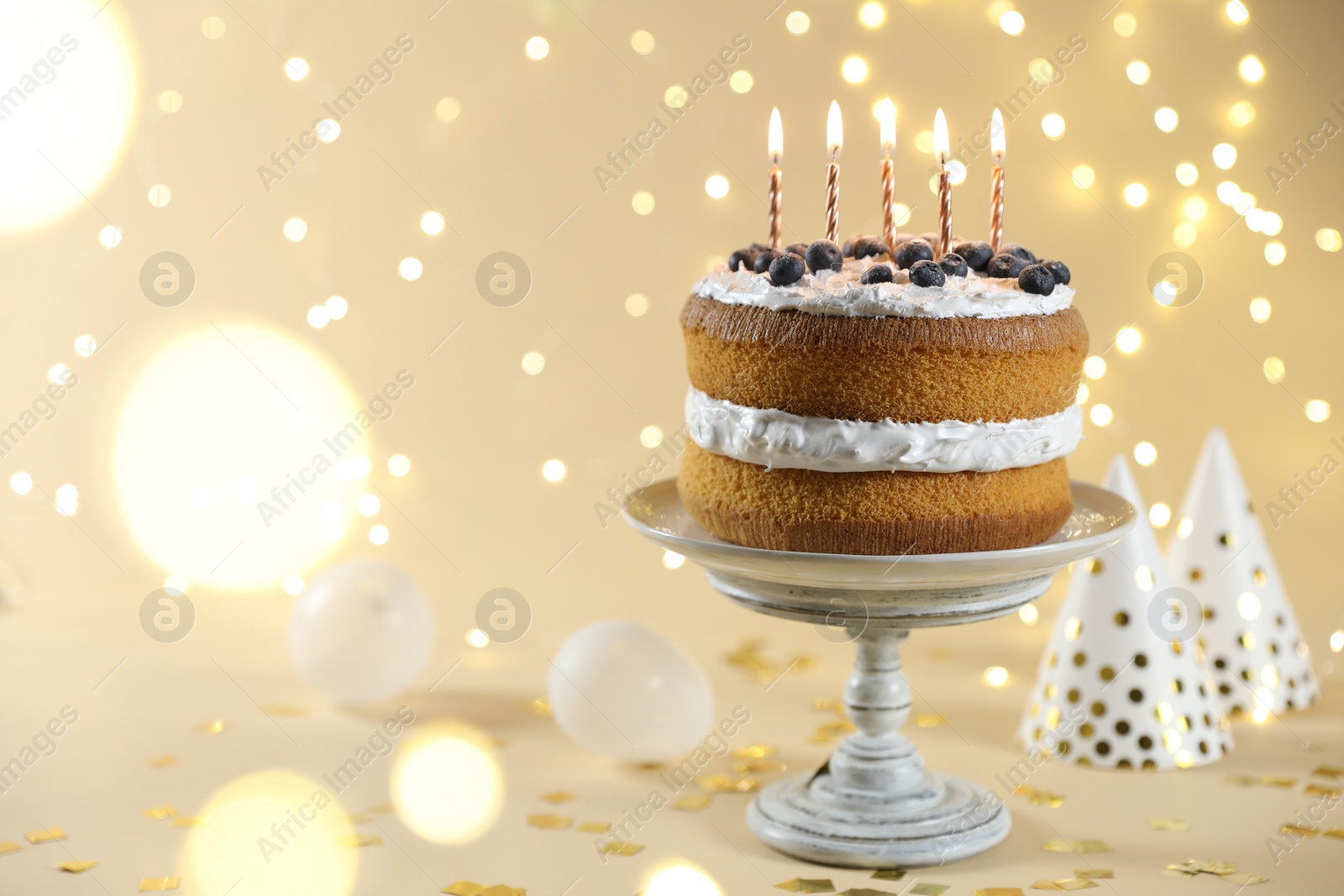 Photo of Tasty cake with burning candles on beige background against blurred lights. Space for text