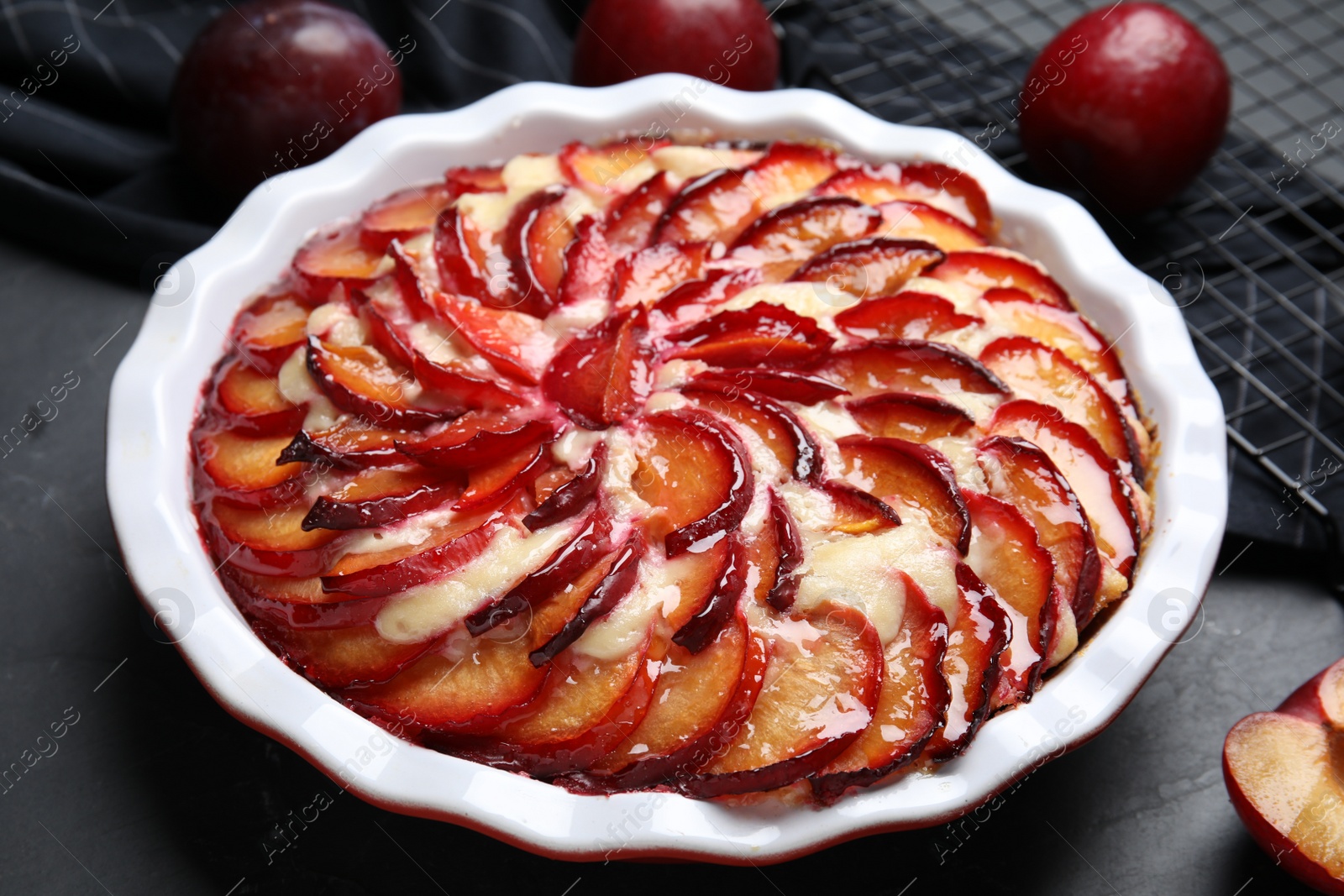 Photo of Delicious cake with plums on black table, closeup