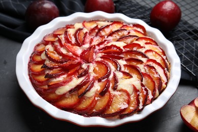 Delicious cake with plums on black table, closeup