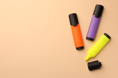 Bright color markers on beige background, flat lay. Space for text