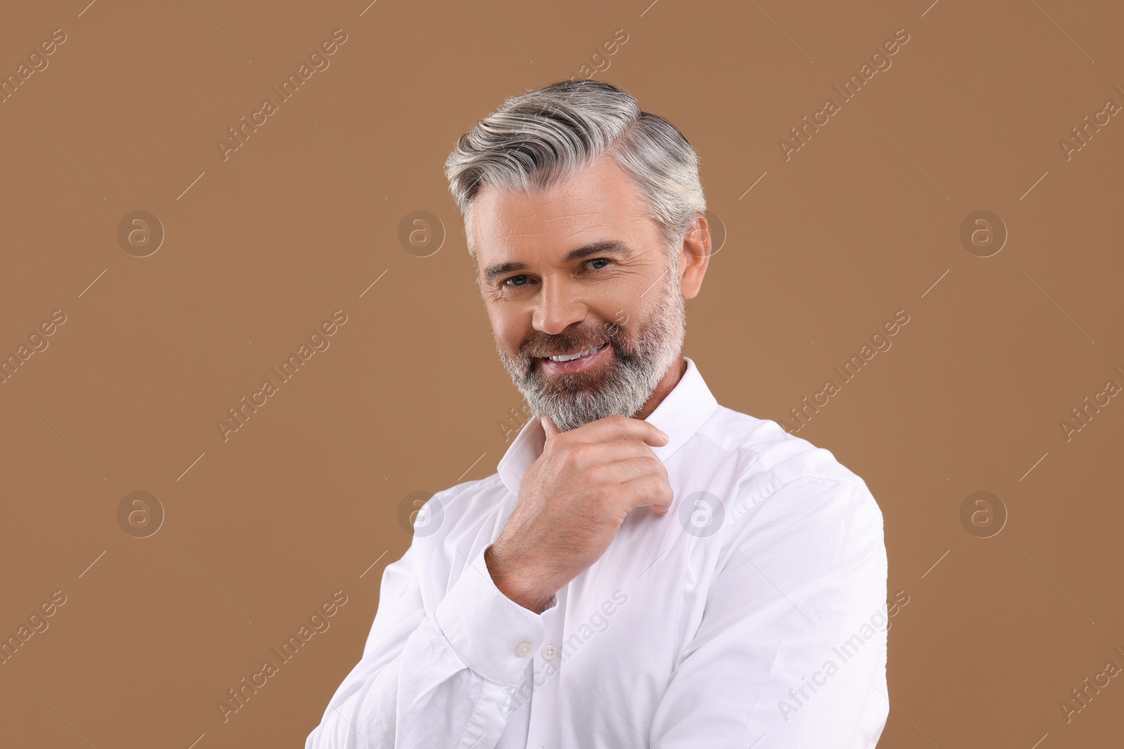 Photo of Portrait of smiling man with beautiful hairstyle on light brown background