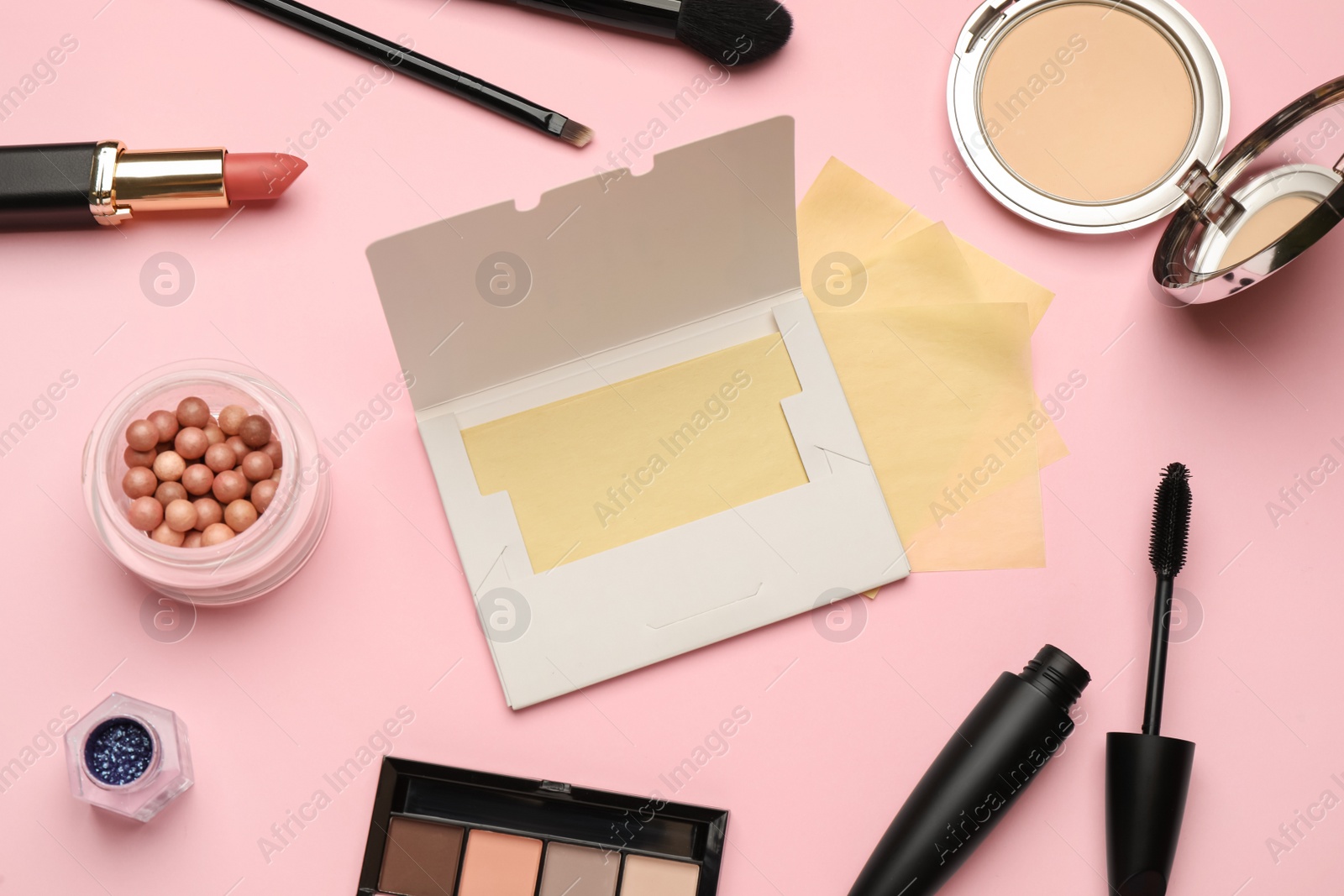 Photo of Facial oil blotting tissues and different decorative cosmetics on pink background, flat lay. Mattifying wipes