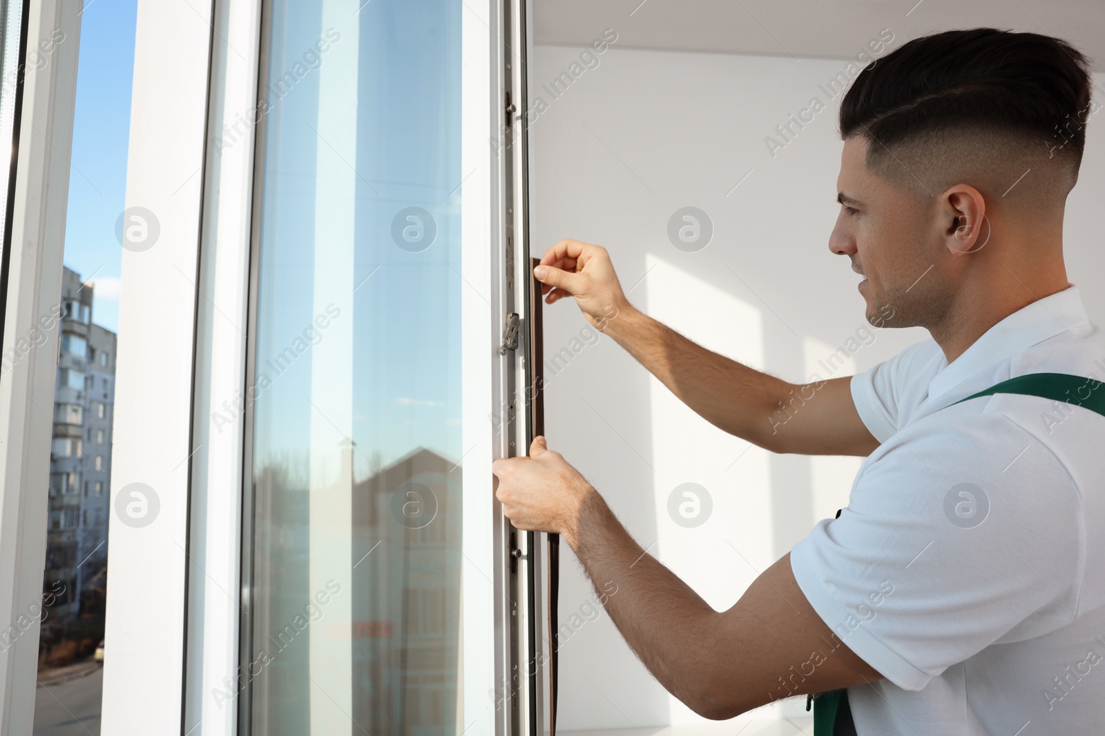 Photo of Worker putting rubber draught strip onto window indoors