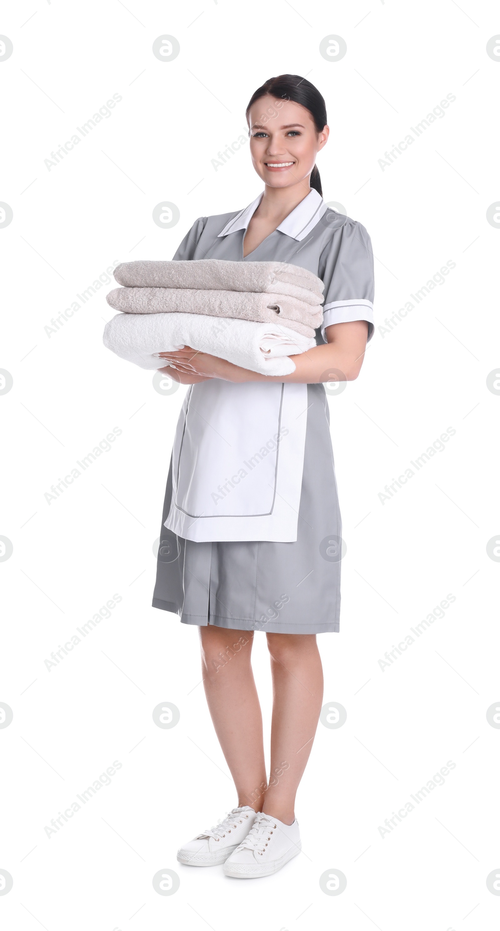 Photo of Young chambermaid holding stack of fresh towels on white background