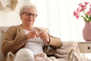 Photo of Elderly woman knitting at home. Creative hobby