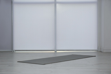 Unrolled grey yoga mat on floor in room