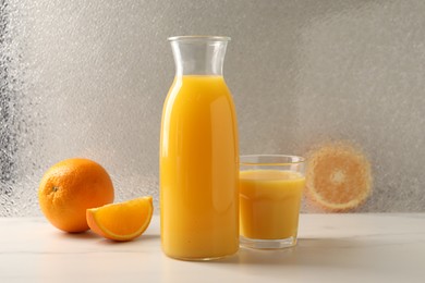 Photo of Tasty fresh oranges and juice on white marble table