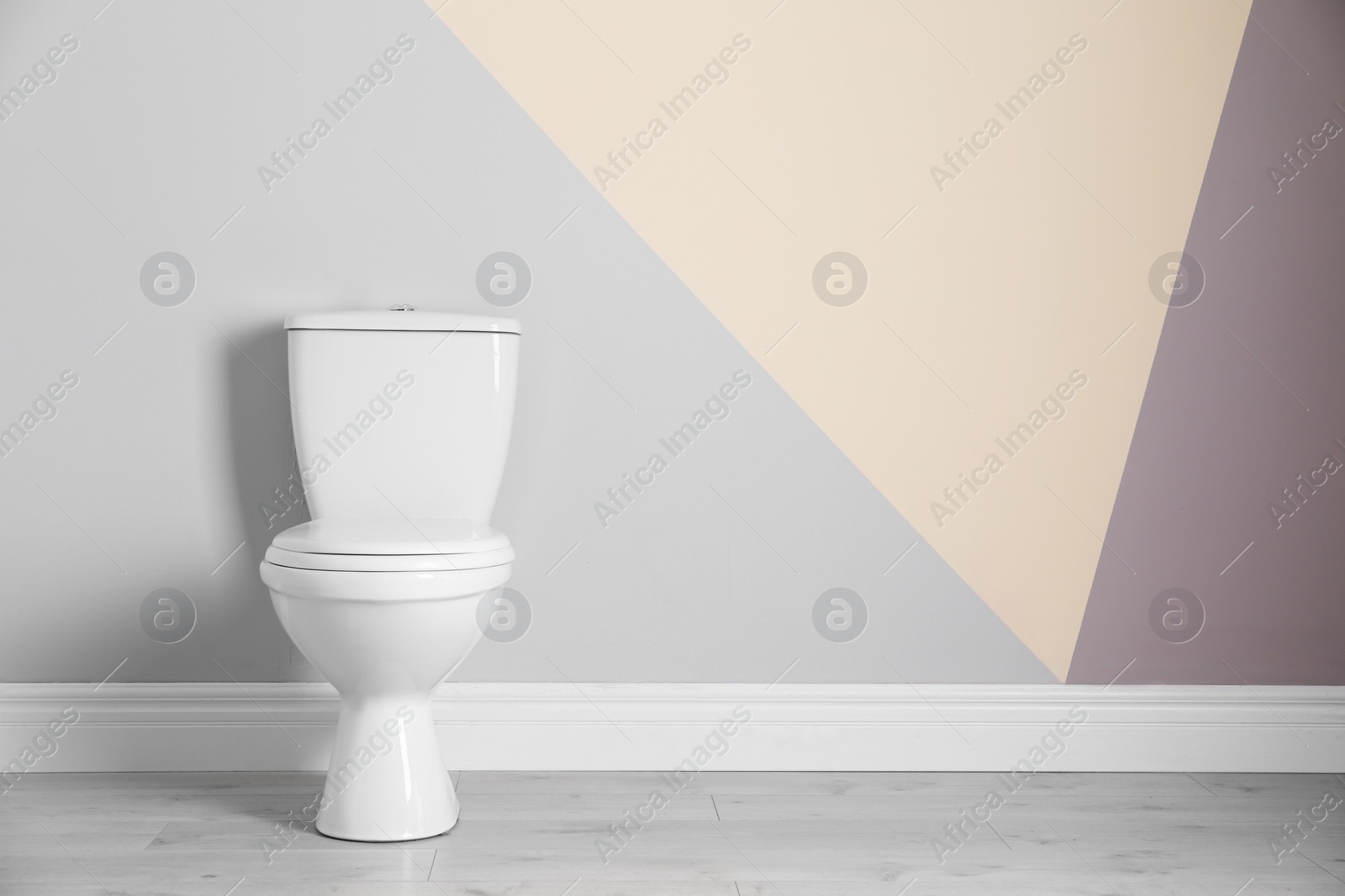 Photo of New toilet bowl near color wall indoors. Space for text