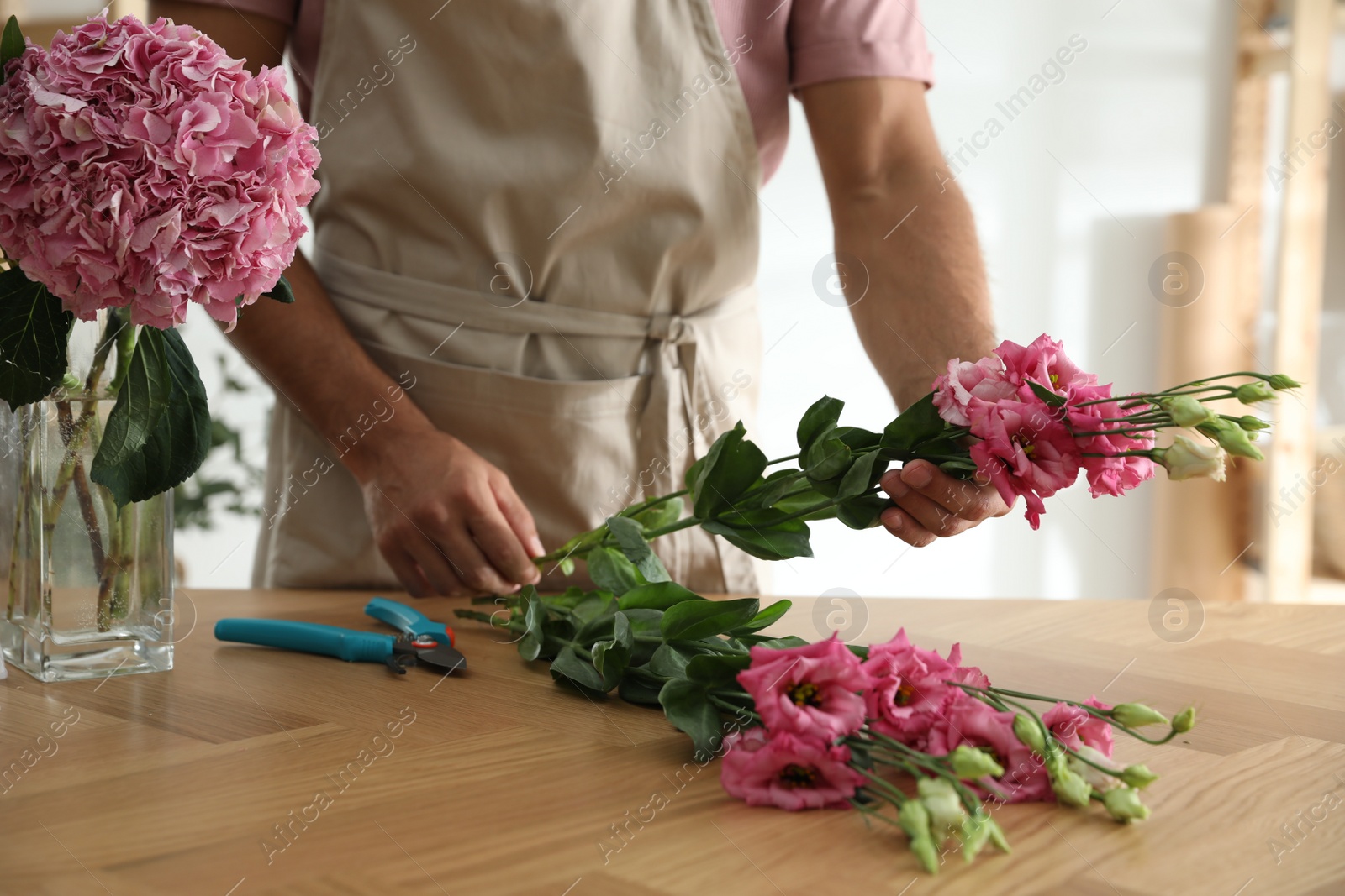 Photo of Florist making beautiful bouquet at table in workshop, closeup