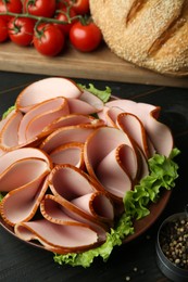 Photo of Slices of delicious boiled sausage and other products on dark wooden table, above view