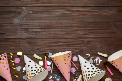 Photo of Colorful party hats and other festive items on wooden table, flat lay. Space for text