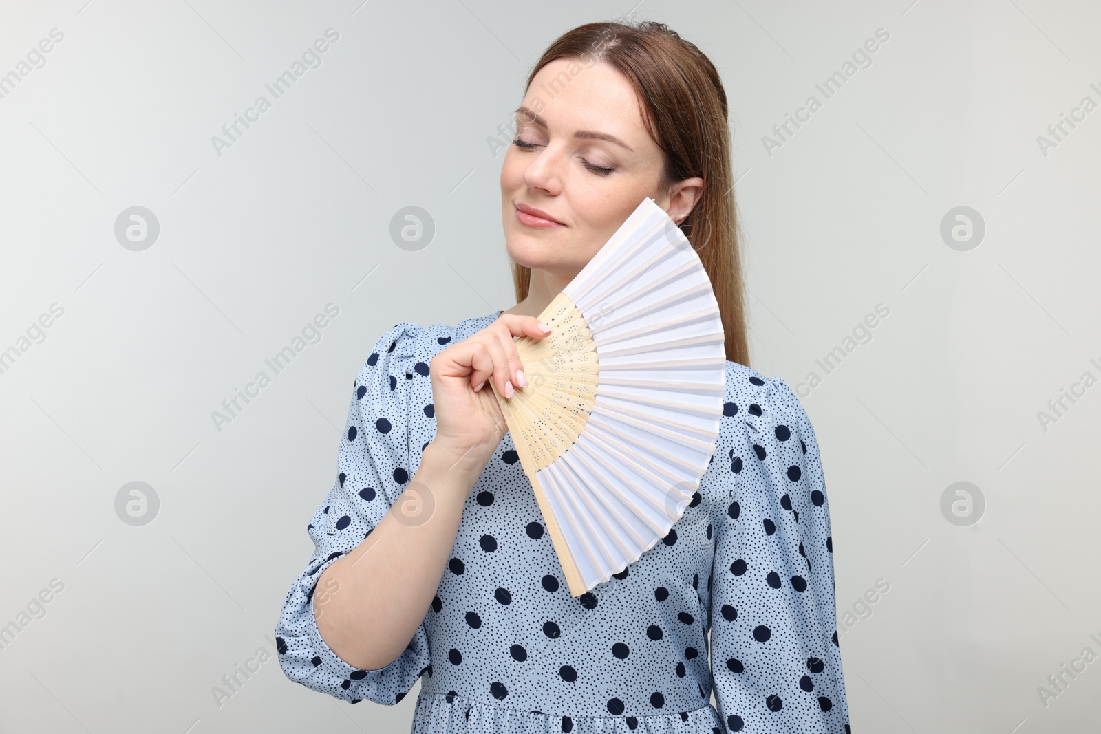 Photo of Woman with hand fan on light grey background