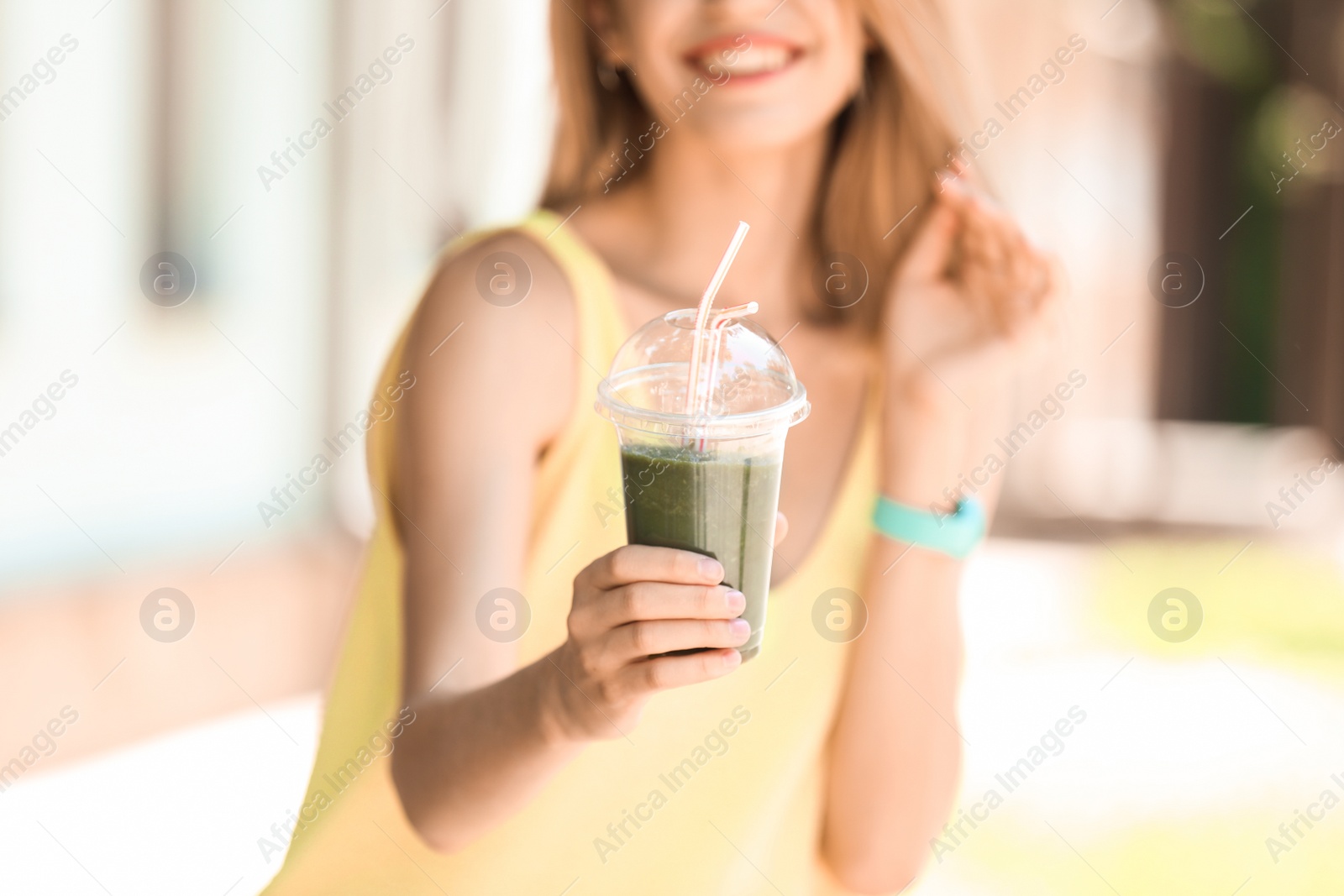 Photo of Young woman with plastic cup of healthy smoothie outdoors