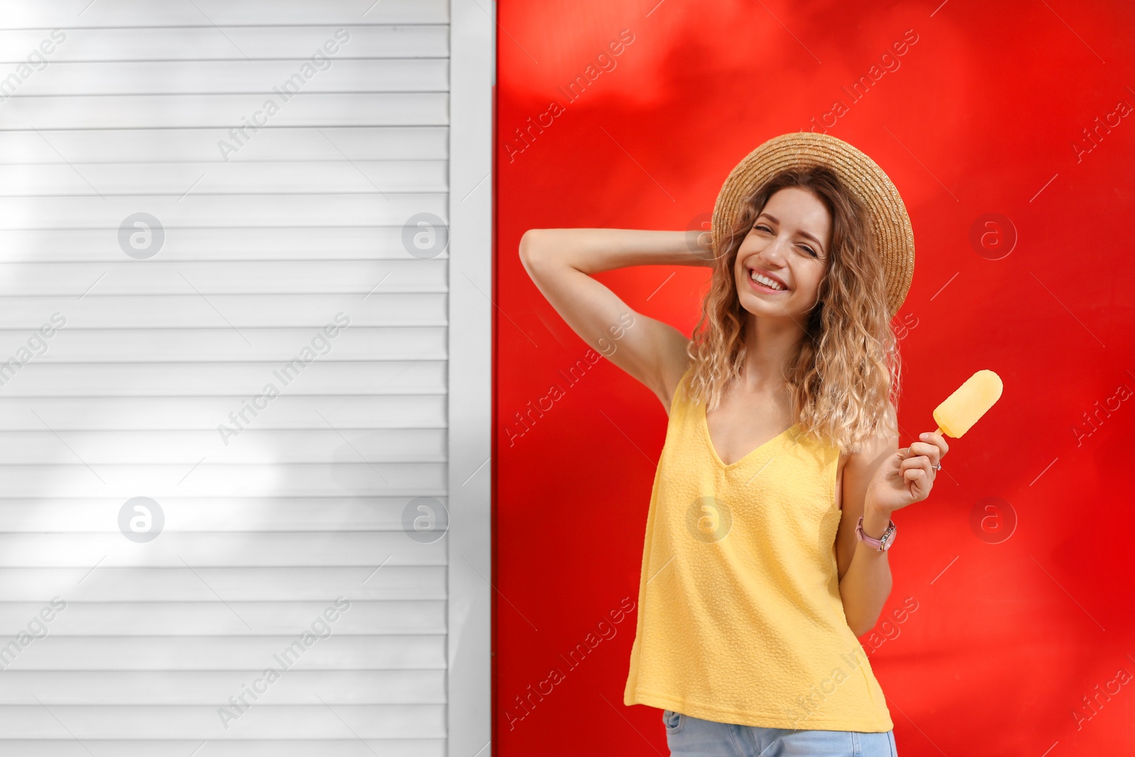 Photo of Happy young woman with delicious ice cream near color wall. Space for text