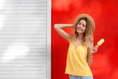 Photo of Happy young woman with delicious ice cream near color wall. Space for text