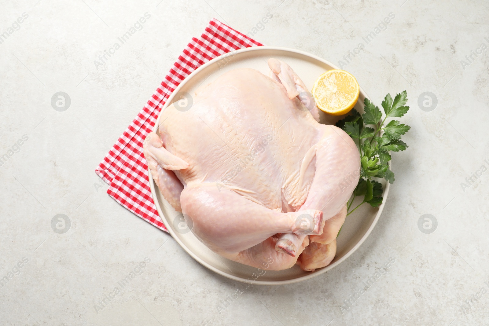 Photo of Fresh raw chicken with lemon and parsley on light grey table, top view