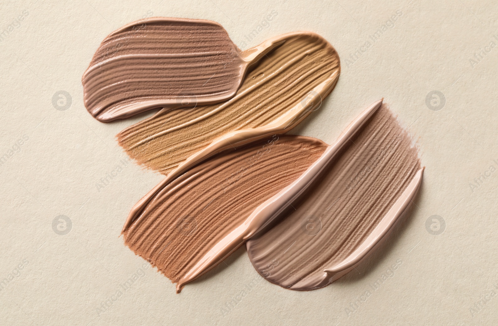 Image of Different shades of liquid foundation on beige background, top view