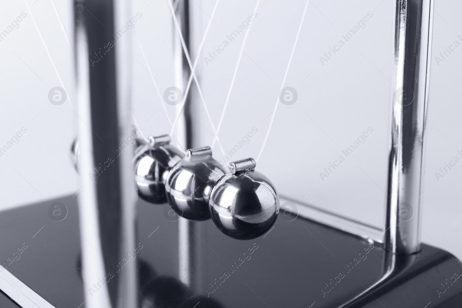 Photo of Newton's cradle on light background, closeup. Physics law of energy conservation