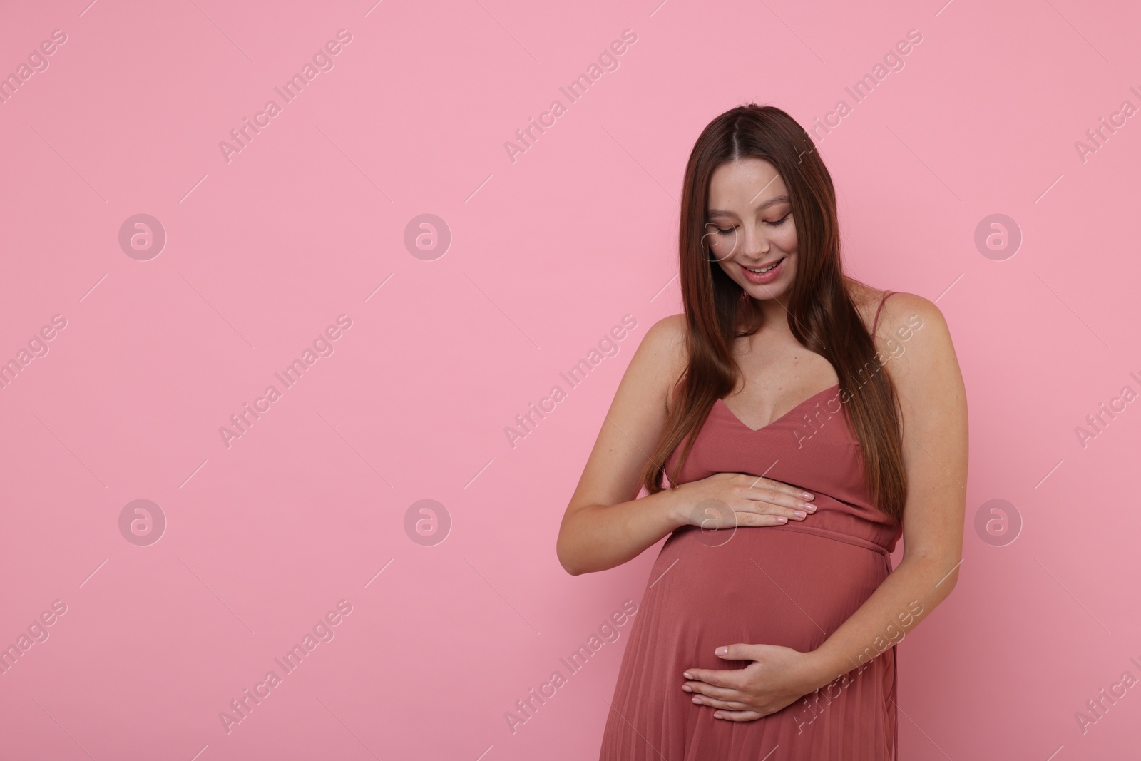 Photo of Beautiful pregnant woman in dress on pink background, space for text