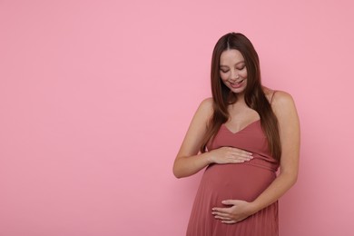 Beautiful pregnant woman in dress on pink background, space for text