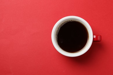 Photo of Aromatic coffee in cup on red background, top view. Space for text