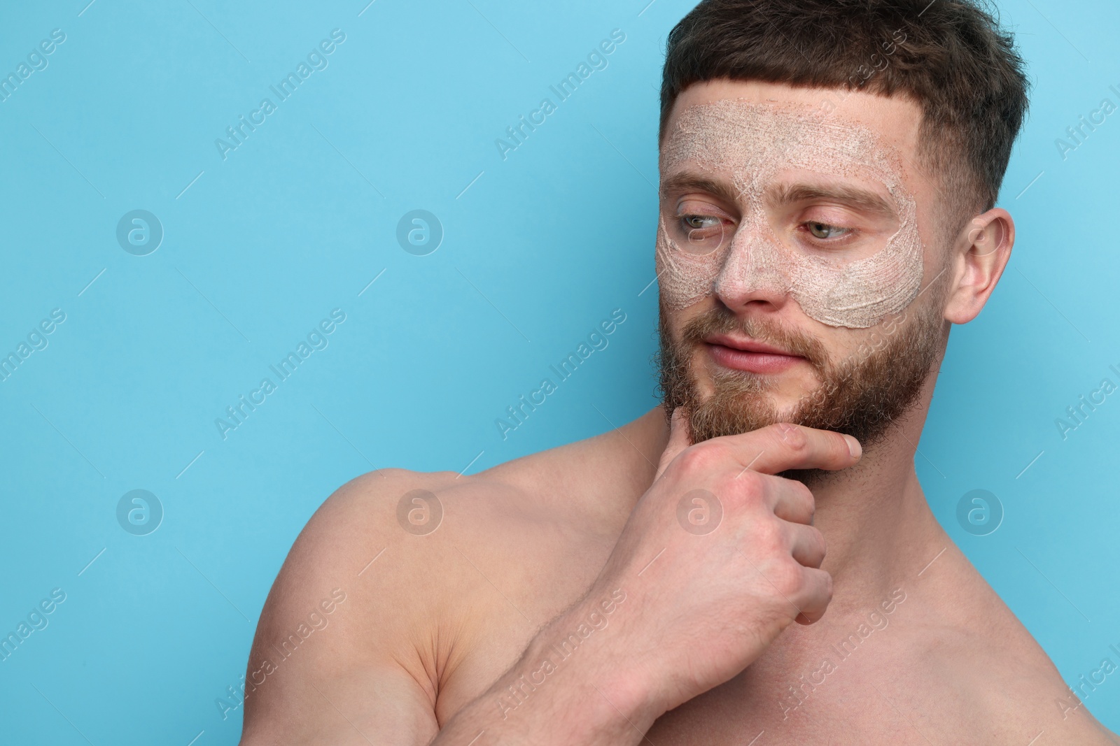 Photo of Handsome man with facial mask on his face against light blue background