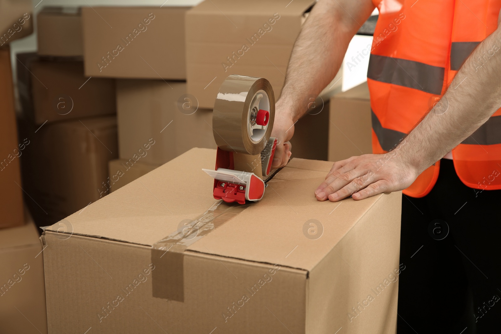 Photo of Worker taping cardboard box indoors, closeup view