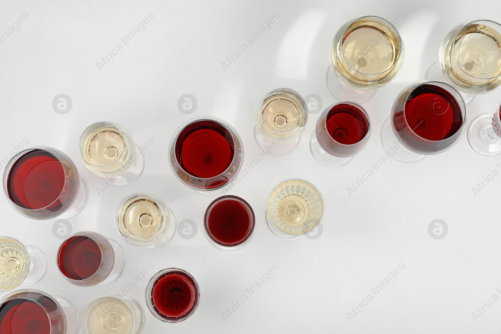 Photo of Glass of red and white wines on light background, top view