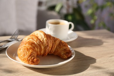 Photo of Delicious fresh croissant served on wooden table, closeup. Space for text