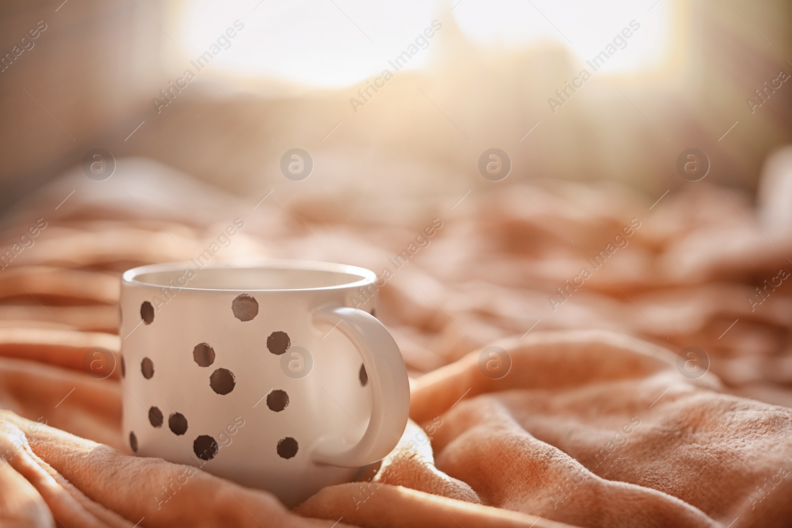 Photo of Cup of hot coffee on soft plaid