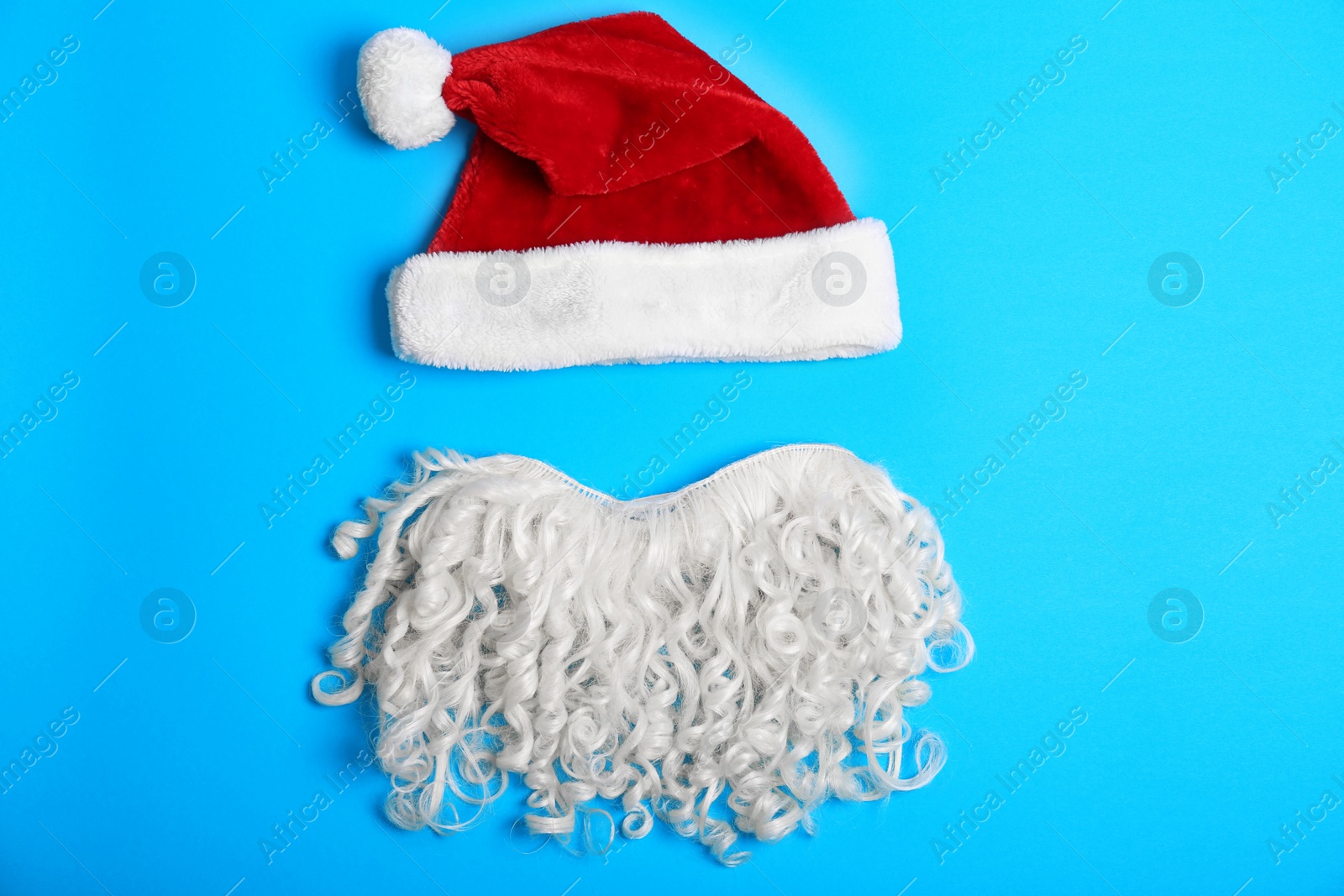 Photo of Santa Claus red hat and beard on color background, top view