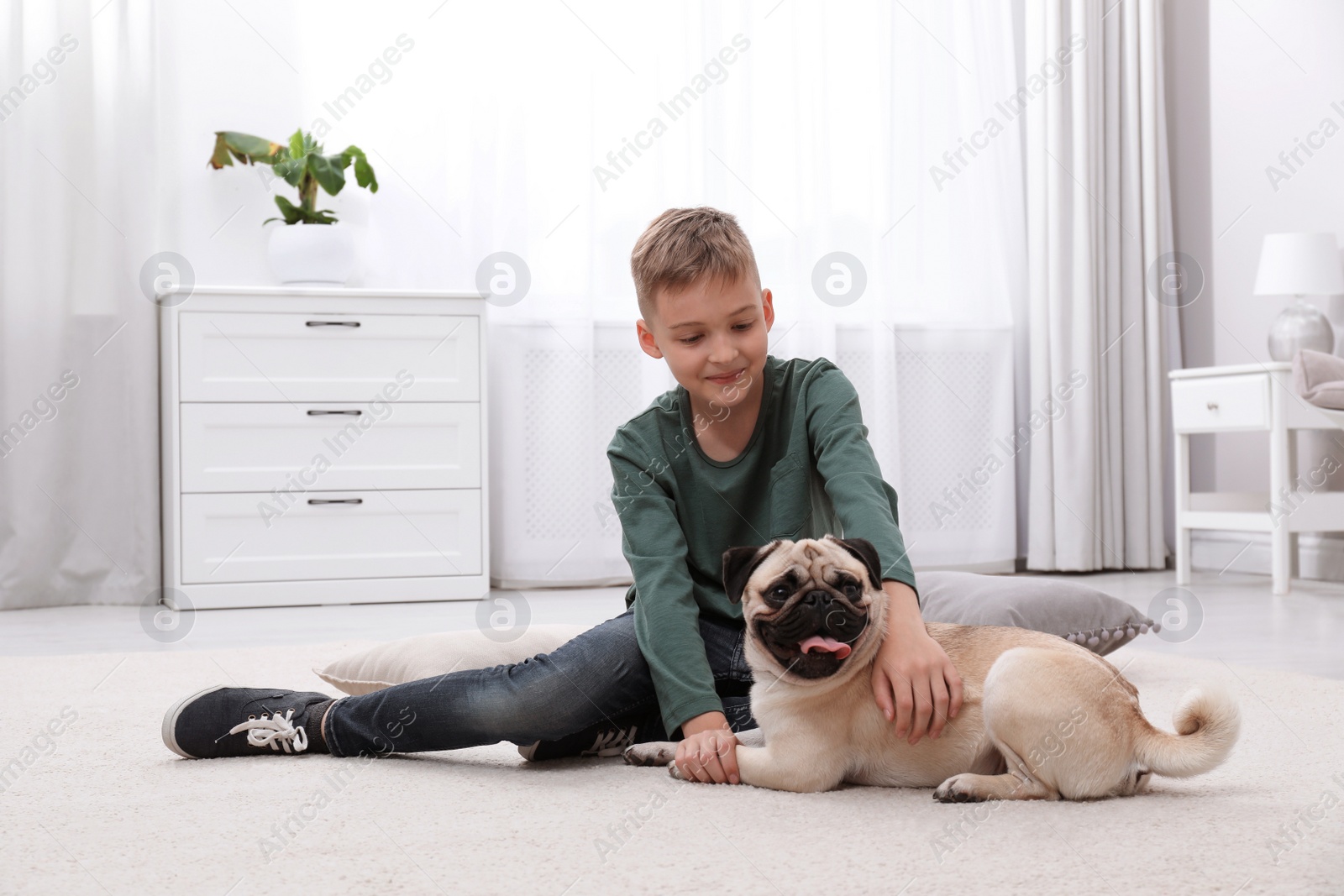 Photo of Boy with his cute pug on floor at home