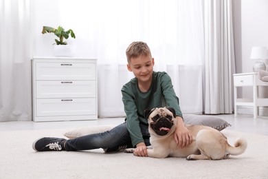 Boy with his cute pug on floor at home