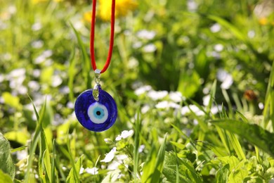 Photo of Evil eye amulet against green meadow outdoors