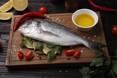 Photo of Composition with fresh raw dorado fish and spices on black wooden table